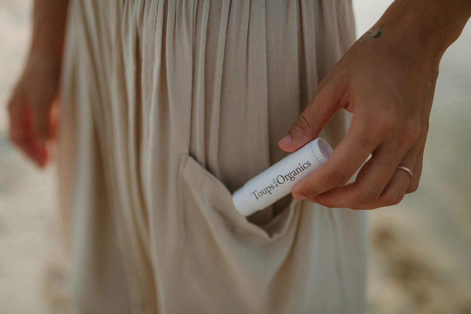 woman-puts-emu-oil-and-tallow-balm-skincare-stick-in-her-skirt-pocket