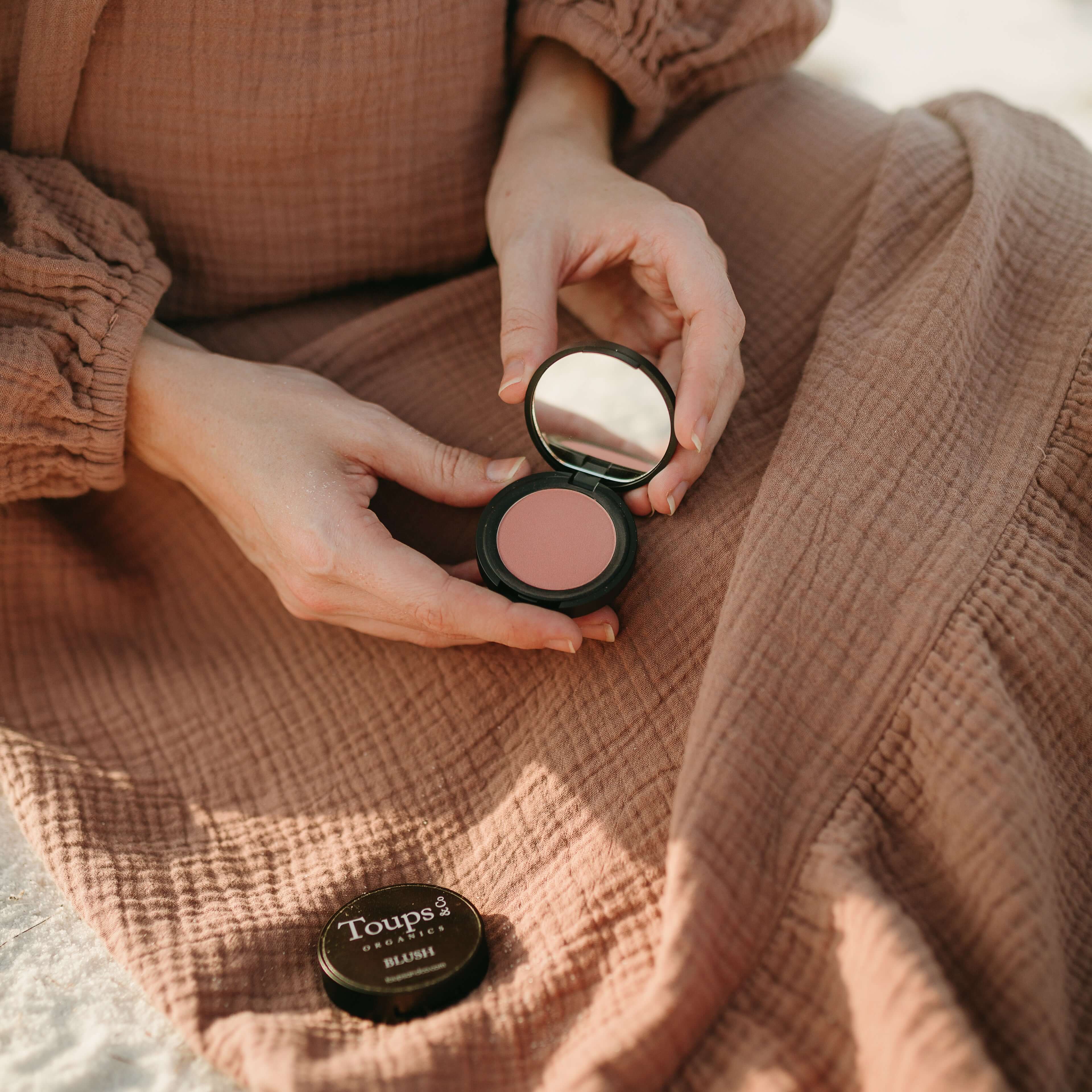 woman-holds-nontoxic-powder-blush-product-open-to-show-pigment