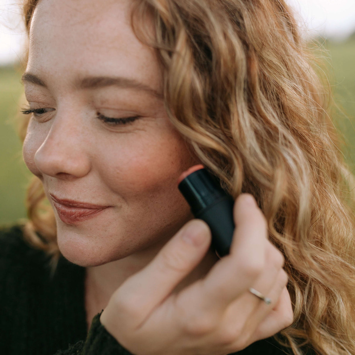 woman-smiles-while-applying-nontoxic-cream-blush