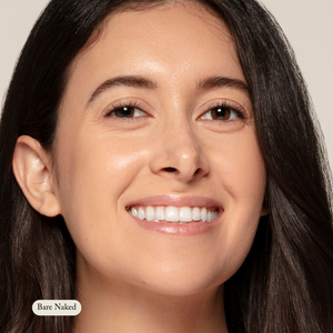A woman with long dark hair and clear skin smiles at the camera, radiating natural hydration. The label Toups and Co Organics Concealer appears on the bottom left.