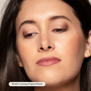 Close-up of a woman with natural makeup, featuring highly pigmented taupe eyeshadow from the Natural Eye Makeup Palette by Toups and Co Organics, soft blush, and mauve lipstick. A label reads: Model is wearing Natural Eye Makeup Palette.