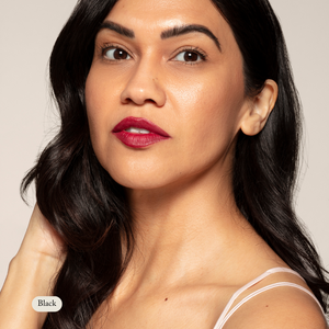 Woman with long, dark hair and bold red lipstick gazes at the camera, her lashes defined by Toups and Co Organics Long Lash Mascara, wearing a white spaghetti strap top against a neutral background.