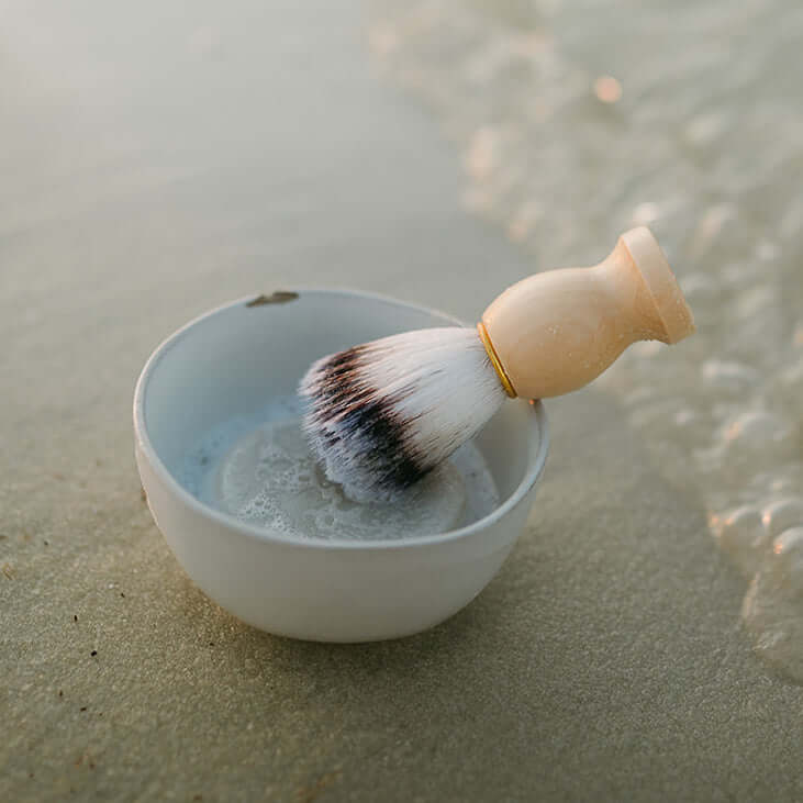 mens-shave-brush-displayed-with-clay-bowl-on-beach-scene
