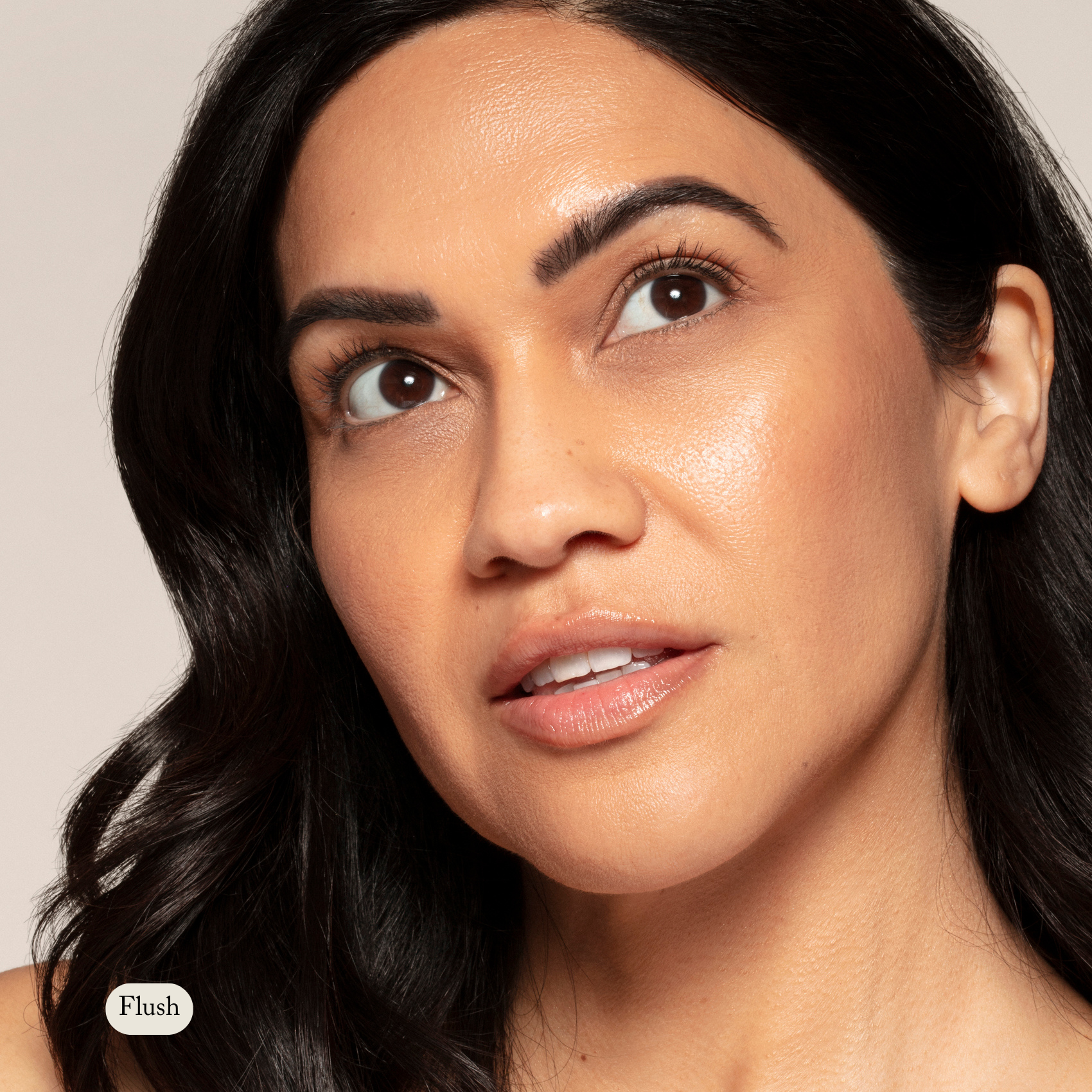 A woman with medium skin and dark wavy hair looks upward, wearing natural makeup with a dewy finish and a touch of Toups and Co Organics Natural Pressed Blush.