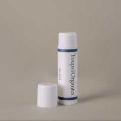 An upright white tube of the Toups and Co Organics Sun Stick is displayed with its cap beside it on a plain beige background, delivering effective sun protection and nourishing skincare.