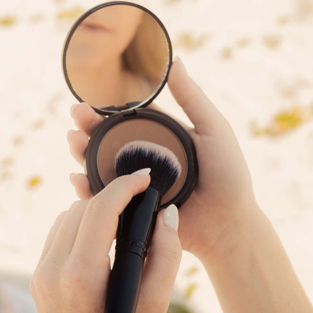 lifestyle-photo-of-woman-dipping-her-makeup-brush-into-nontoxic-bronzer-makeup