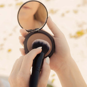 lifestyle-photo-of-woman-dipping-her-makeup-brush-into-nontoxic-bronzer-makeup