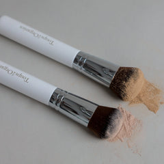 Two make brushes with two shades of Toups & Co's non-toxic mineral foundation on them. 