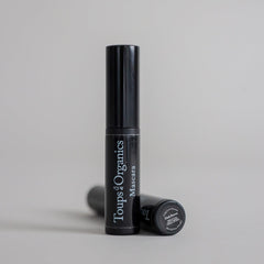 Product photography featuring two mascara tubes displayed on a clean grey seamless background, showcasing a sleek beauty cosmetic presentation.