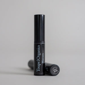 Product photography featuring two mascara tubes displayed on a clean grey seamless background, showcasing a sleek beauty cosmetic presentation.