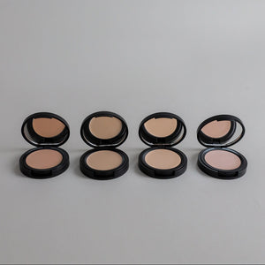 Four Toups & Co non-toxic concealers displayed open to showcase a range of complexion shades against a clean grey seamless background. A simple, modern product photo highlighting natural makeup and versatile beauty essentials.