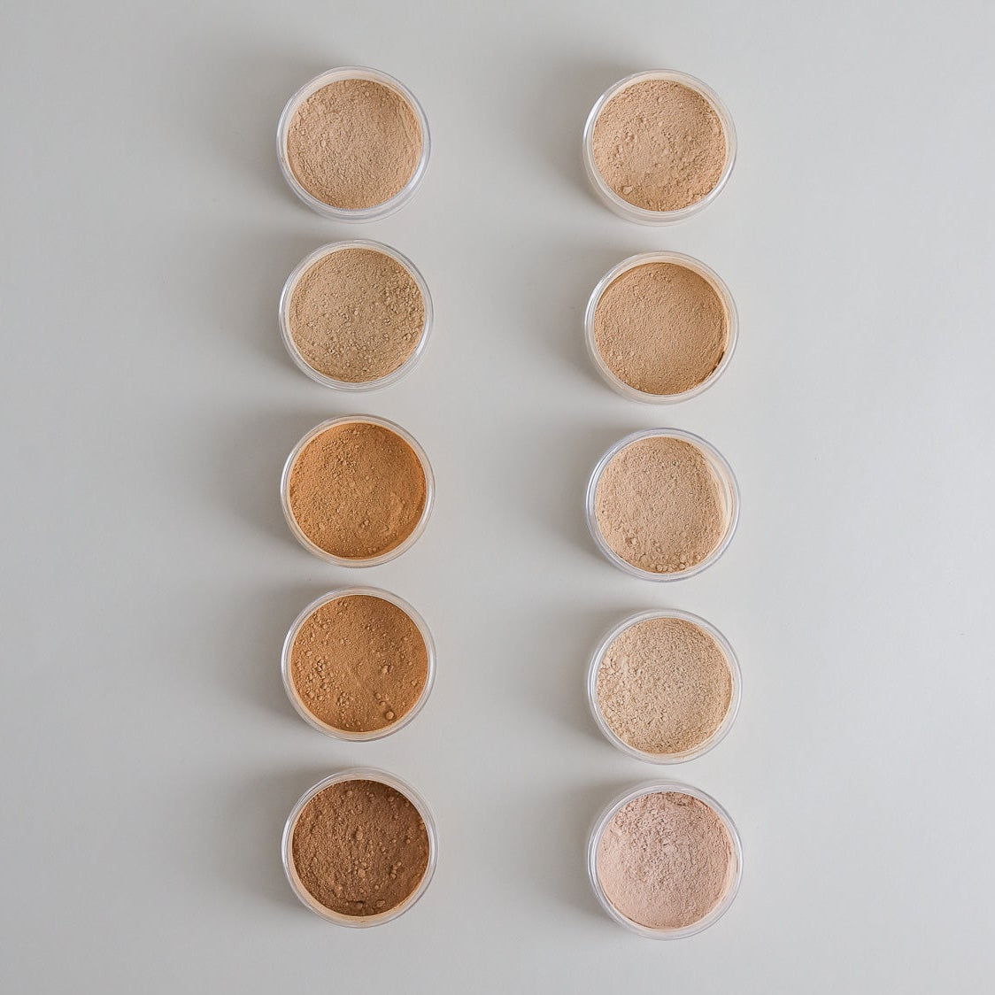 Ten shades of non-toxic mineral foundation powder in a flat lay shade range
