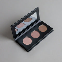 Close-up product photo of a three-shade eyeshadow palette displayed on a clean grey seamless background, showcasing versatile eyeshadow colors and a modern beauty aesthetic.