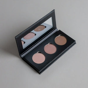 Close-up product photo of a three-shade eyeshadow palette displayed on a clean grey seamless background, showcasing versatile eyeshadow colors and a modern beauty aesthetic.