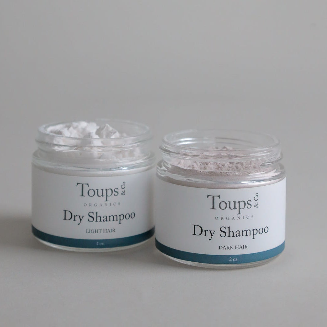 Two jars of Toups and Co Organics Dry Shampoo, one for light hair and one for dark hair, each with 2 oz of product. Ideal for a quick scalp refresh, this dry shampoo effectively absorbs oil to help your hair look and feel clean between washes.