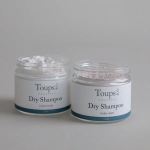 Two jars of Toups and Co Organics Dry Shampoo, one for light hair and one for dark hair, each with 2 oz of product. Ideal for a quick scalp refresh, this dry shampoo effectively absorbs oil to help your hair look and feel clean between washes.