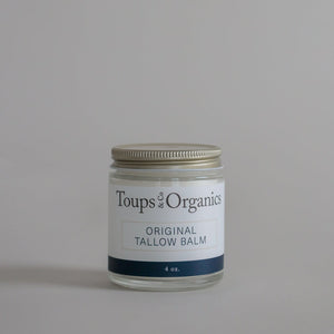 A glass jar labeled Tallow Balm - Original by Toups and Co Organics, 4 oz, offers whole-body moisture for dry, sensitive skin on a plain gray background.