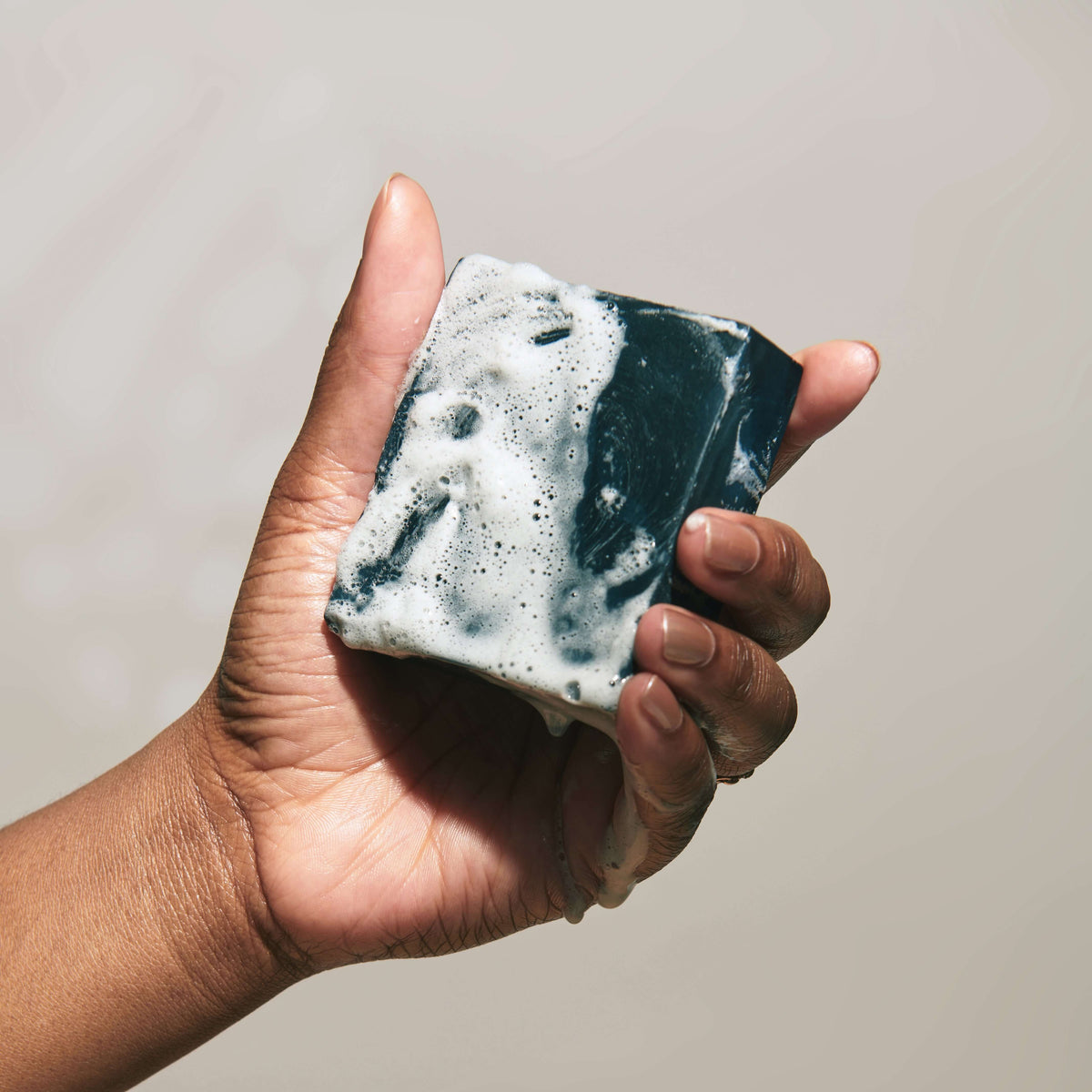hand-holds-lathered-activated-charcoal-tallow-soap